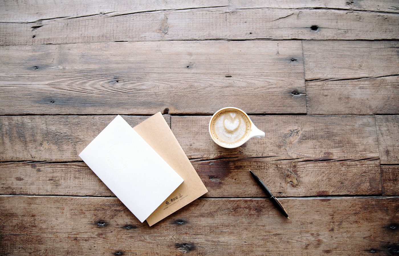 Carnet, crayon et tasse posés sur un plan de travail en bois