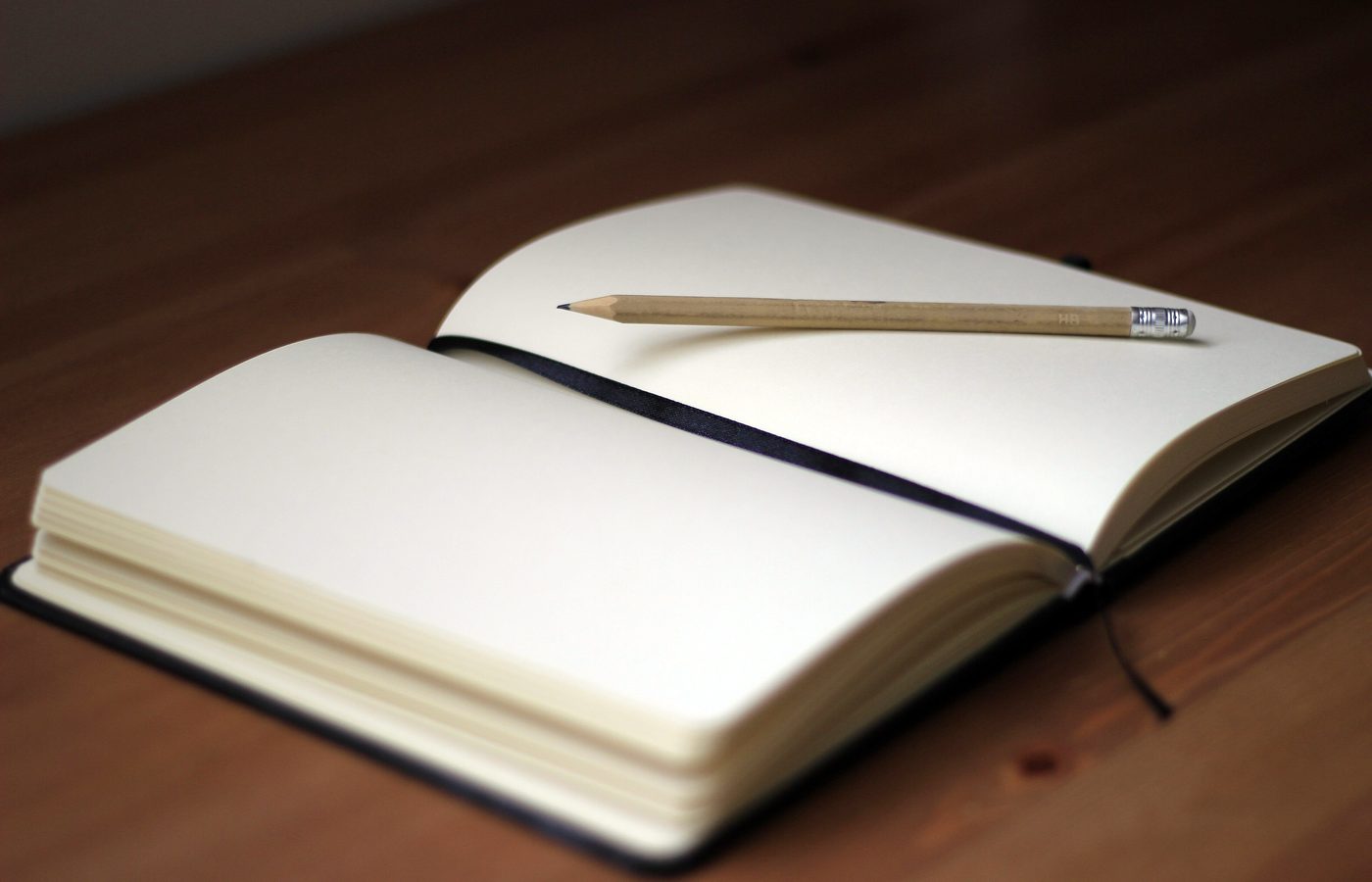 Carnet ouvert sur des pages blanches, un crayon posé dessus
